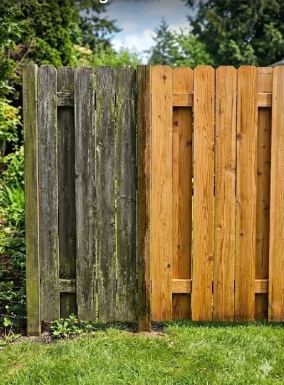 Wood fence half cleaned showing before and after pressure washing