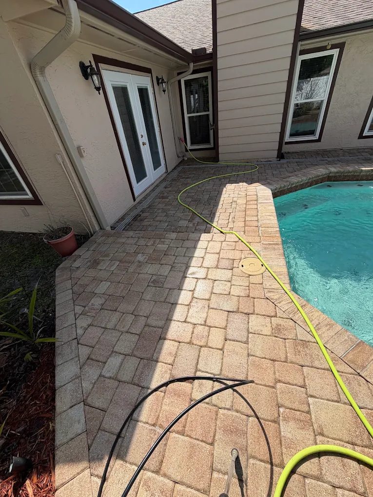 Clean brick paver pool deck with hoses ready for service